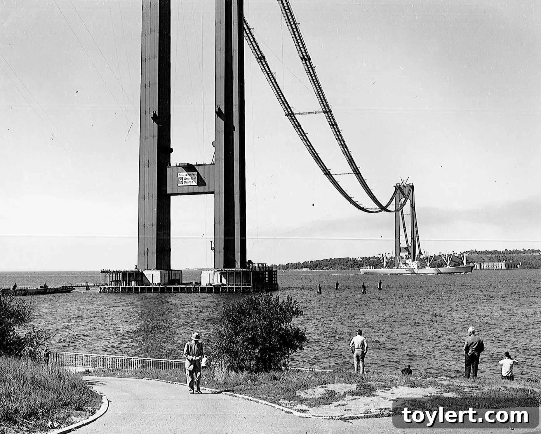 Historic aerial view of the Verrazano-Narrows Bridge under construction, showcasing the emerging towers and nascent cable work over the water