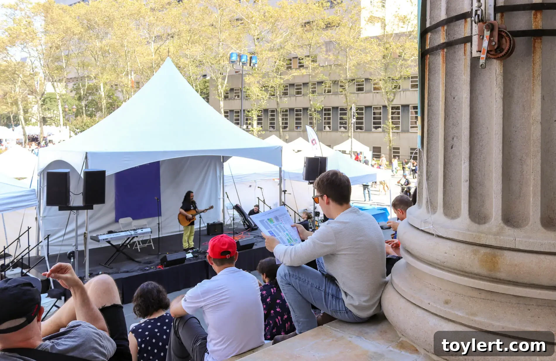 Brooklyn Book Festival Unites Sun and Stories 2 Attendees enjoying the vibrant atmosphere of the Brooklyn Book Festival in Columbus Park, with numerous book stalls under a sunny sky.