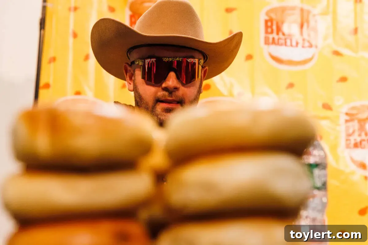 BagelFest Winter Games Debut in Downtown Brooklyn with Rolling, Tossing, and Devouring 2 A competitive eater, Harry Harkins, focuses intently on a formidable stack of fresh bagels, preparing for the BagelFest Winter Games' bagel-eating competition.