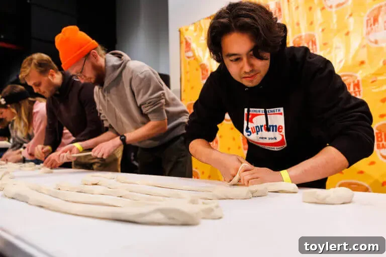 BagelFest Winter Games Debut in Downtown Brooklyn with Rolling, Tossing, and Devouring 3 Bennet Adamson participates intensely in the bagel dough-rolling competition at BagelFest, demonstrating focus and skill.