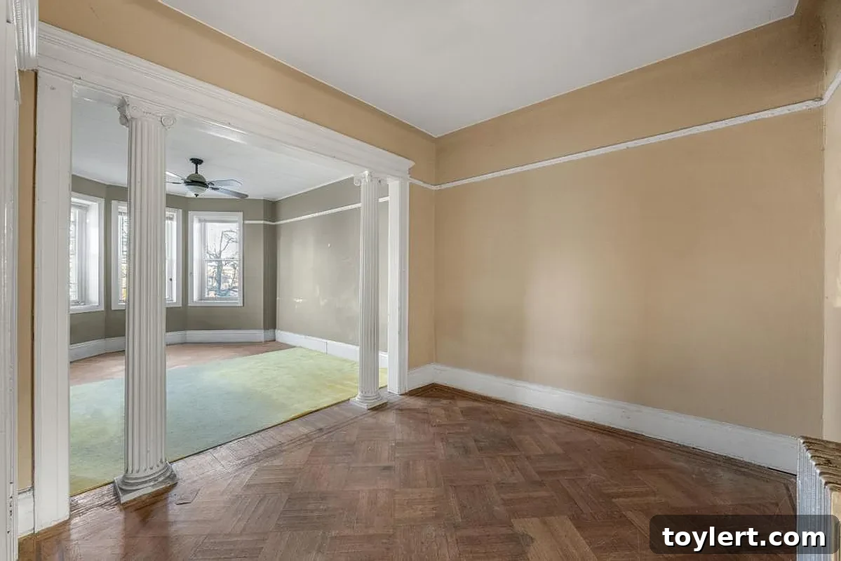 Gracious parlor room with ornate architectural columns and polished hardwood floor, showcasing classic Brooklyn design elements ideal for sophisticated living and entertaining.